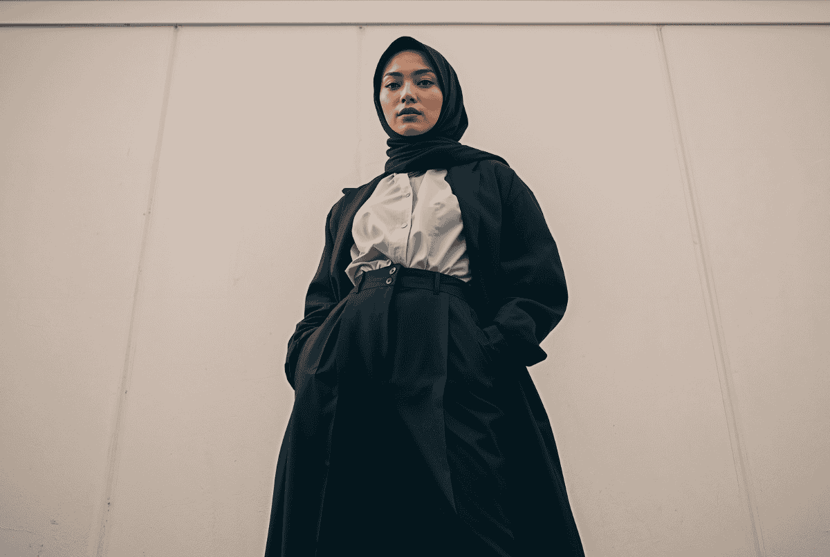 Wanita berhijab monokrom modern dengan outer panjang dan celana high-waist untuk ilusi tinggi