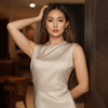 Wanita Indonesia mengenakan dress simple beige di kafe modern dengan gaya elegan.