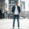 Pria dengan gaya tren fashion simpel memakai kaos putih, jeans, dan jaket denim.