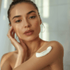 Wanita mengoleskan body lotion setelah mandi di kamar mandi modern bernuansa lembut